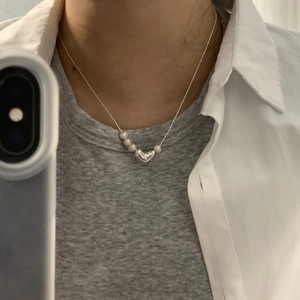 Detail of silver heart pendant necklace with freshwater pearls shown on neck
