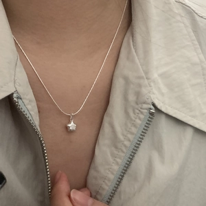 Detail of S925 silver star pendant necklace worn on a grey jacket for minimalist style