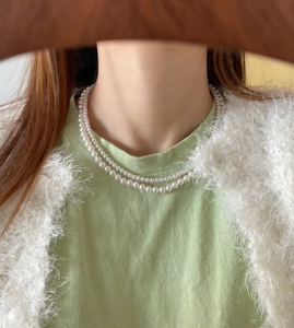 Close-up of elegant double-layered white pearl necklace worn by a female model