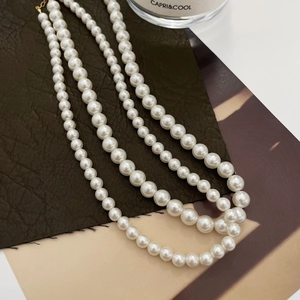 Detailed close-up of triple-layered pearl necklace with golden clasp on leather texture
