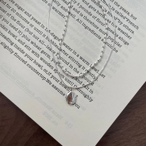 Detail of S925 silver double-layered necklace with hammered oval pendant on book page