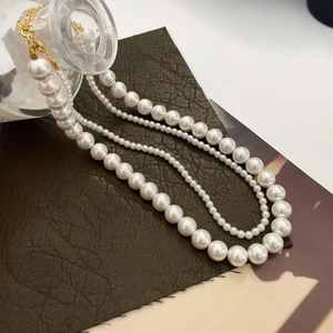 Close-up of triple-layered white pearl necklace with elegant golden lobster clasps