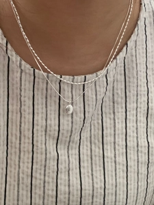 Detail of S925 sterling silver double layer necklace with oval pendant on striped shirt