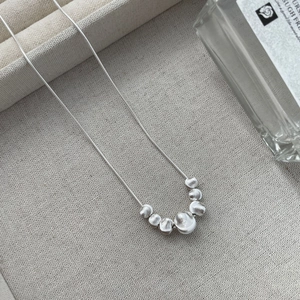 Detailed view of S925 silver snake chain with frosted beads on beige linen tray
