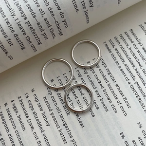 Vue détaillée de trois bagues en argent sterling S925 poli posées sur un livre vintage