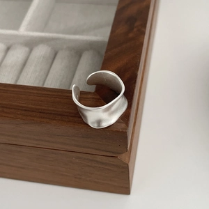 Minimalist matte S925 sterling silver adjustable wave ring on a dark wooden box