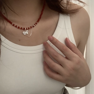 Detail of red agate bead necklace with silver bow pendant and tassel on neck