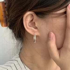 Detailansicht von zweilagigen silbernen Creolen am Ohr für einen minimalistischen Stil