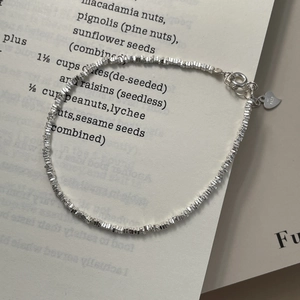 Détail macro du bracelet à billes en argent sterling S925 avec breloque cœur sur livre