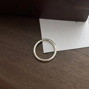 Bague minimaliste en argent sterling S925 poli posée sur une surface en bois sombre