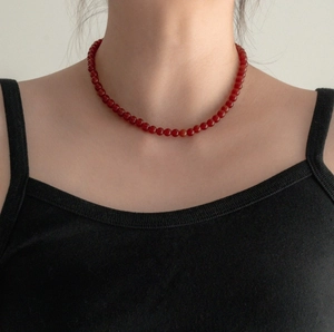Close-up of a minimalist S925 sterling silver necklace with polished red agate beads