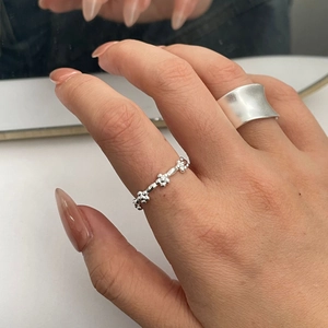 Detailed macro shot of silver floral engraved ring and matte minimalist wide band ring