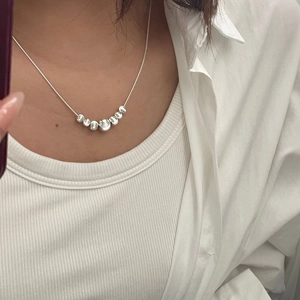 Detail of S925 sterling silver snake chain necklace with seven polished beads on model