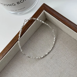 Gros plan du bracelet en argent S925 avec perles facettées et fermoir mousqueton sur plateau