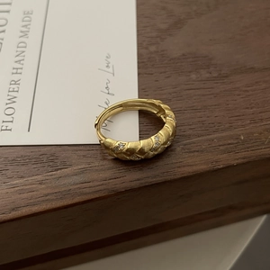 Detail of vintage wheat ear ring featuring brushed texture and zircon stones on a wooden tray
