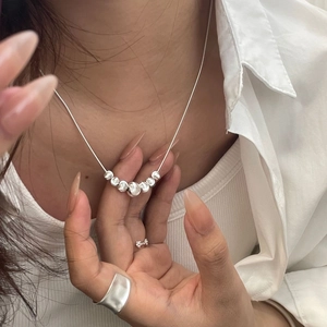 Detailed view of S925 sterling silver beaded necklace and minimalist ring set on model