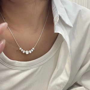 Detailed view of S925 silver necklace with seven gradient metallic beads on the neckline