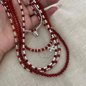 Detail of S925 silver necklace with red agate beads, silver bells and bow pendant