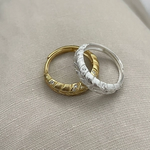 Macro detail of gold and silver feather texture rings with inlaid crystals on fabric
