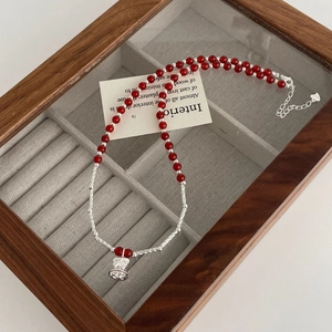 Macro detail of red agate beaded necklace with silver bell pendant and lobster clasp