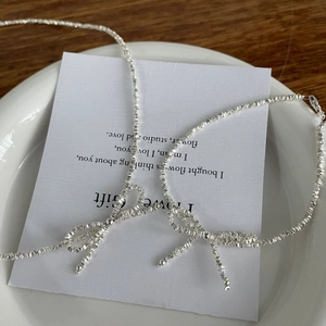 S925 sterling silver bow necklace with irregular silver bead chain on white plate