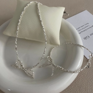 Detailed view of silver bow necklace and bracelet set displayed on a ceramic tray