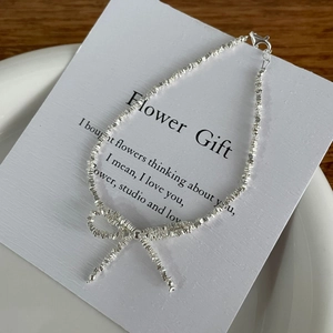 Detailed close-up of a silver bowknot bracelet with multifaceted silver beads and lobster clasp