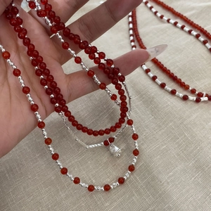 Macro detail of S925 sterling silver beads and red agate necklace with silver bell charm
