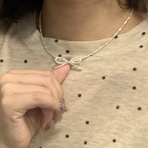 Close-up of sparkling bow pendant necklace in silver finish on model neck