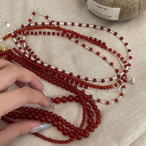Close-up of red agate beads with silver spacers on a natural linen background