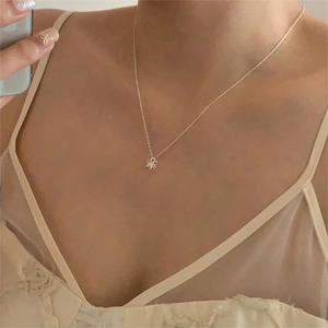 Gros plan du collier fleur en argent S925 minimaliste sur la clavicule d'une femme