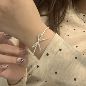 Close-up of a silver bow necklace with zircon stones worn over a polka dot blouse