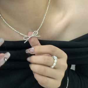 Detail of S925 silver bow necklace and pearl bead ring set worn by model