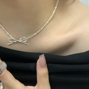 Close-up of S925 silver bow necklace on collarbone with shimmering crushed silver pendant