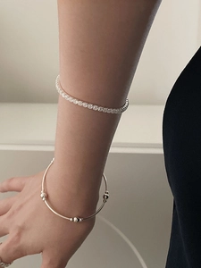Detail of stacked S925 sterling silver tennis bracelet and minimalist beaded cuff on wrist