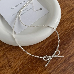 Detailed shot of S925 silver bow necklace with irregular crushed silver texture chain