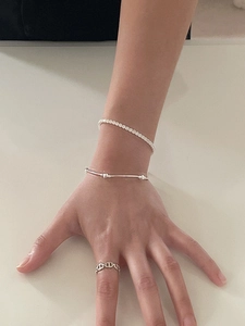 Close-up of stacked S925 sterling silver cz tennis bracelet with minimalist open link ring