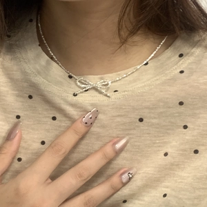 Detailed close-up of a sterling silver bow pendant necklace worn on a person's neck