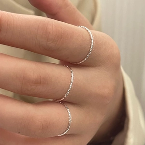 Close-up of three sparkling S925 sterling silver rings with textured diamond-cut finish