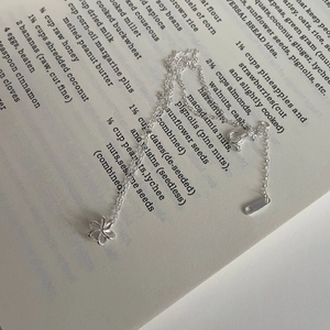 Macro détaillée d'un collier pendentif fleur en argent S925 sur papier vintage