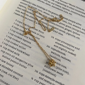 Gros plan d'un collier pendentif fleur dorée posé sur un livre ouvert avec élégance
