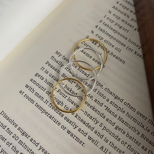 Close-up of minimalist gold and silver stackable thin bands on an open book