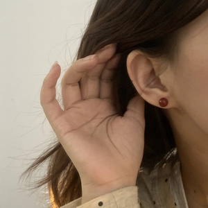 Close-up of red agate stud earrings on ear showing minimalist round gemstone design