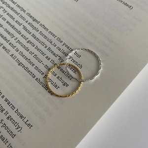 Detail view of thin hammered S925 sterling silver rings in gold and silver on book pages