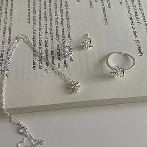 Gros plan d'un ensemble de bijoux en argent 925 motif fleurs sur des pages de livre