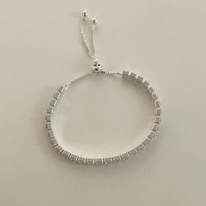 Detailed macro of a silver-tone tennis bracelet featuring square-cut cubic zirconia crystals