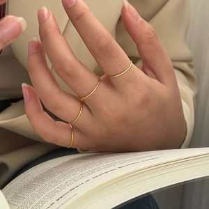 Detail of four gold hammered textured stacking rings on a hand for minimalist style