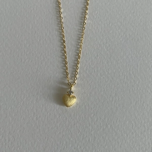 Dettaglio della collana con cuore dorato con finitura opaca e zircone scintillante