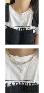 Close-up of S925 silver fish pendant layered with colorful beaded summer necklace