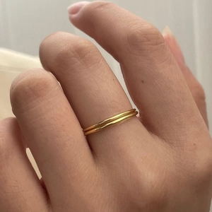 Detail of minimalist gold double-layer thin ring on finger with polished metal finish